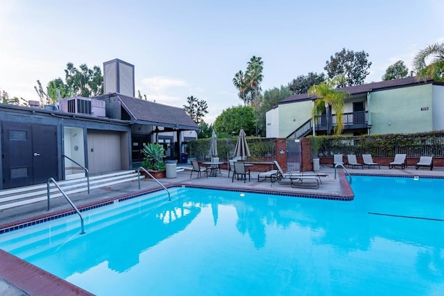 community pool with a patio and fence