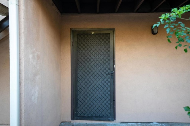 doorway to property featuring stucco siding