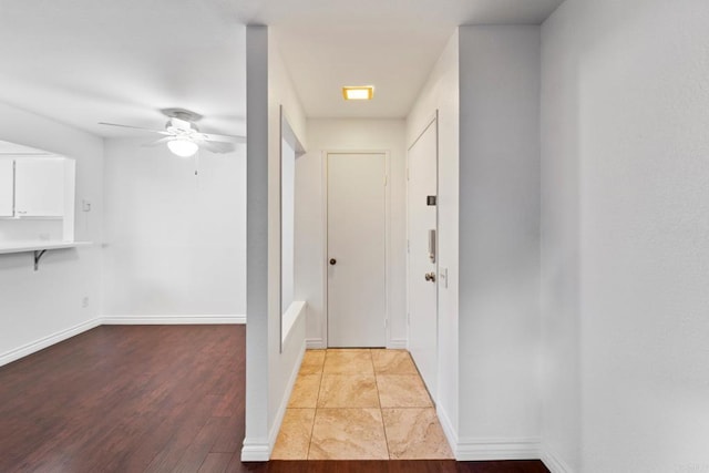 entryway featuring ceiling fan, baseboards, and wood finished floors