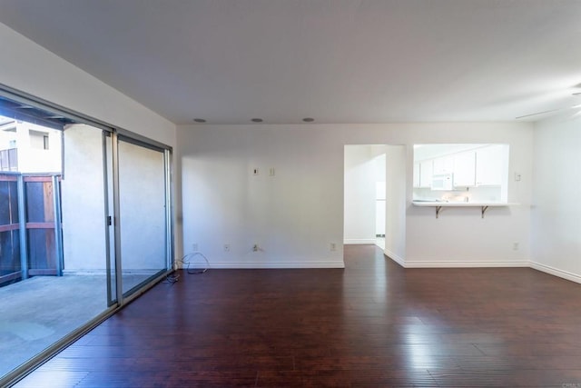 spare room featuring a ceiling fan, baseboards, and wood finished floors