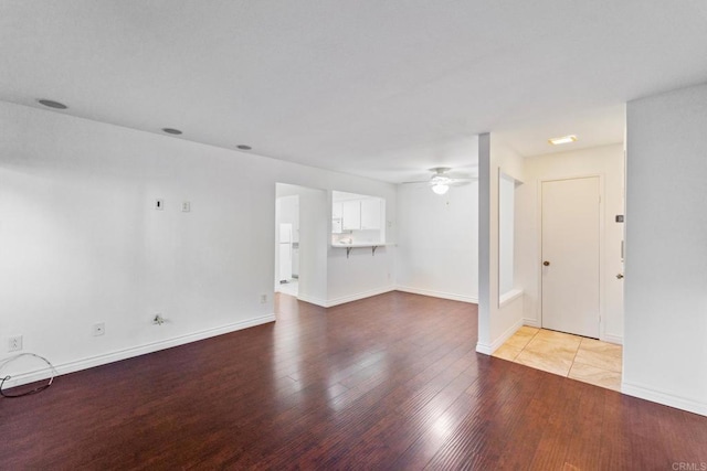 unfurnished living room with wood finished floors, a ceiling fan, and baseboards