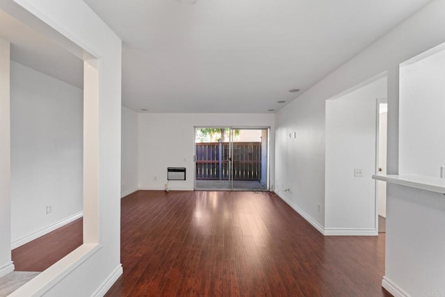 unfurnished room featuring heating unit, baseboards, and wood finished floors