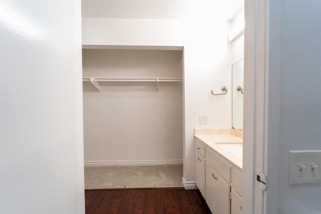 bathroom featuring baseboards, wood finished floors, vanity, and a walk in closet