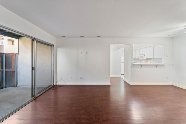 empty room featuring dark wood-style floors, a ceiling fan, and baseboards