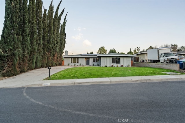 view of front of home with driveway, solar panels, and a front yard