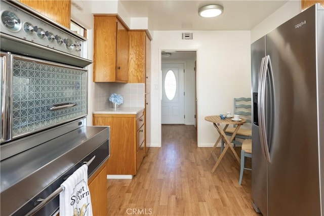 kitchen featuring light wood-style floors, brown cabinetry, backsplash, and stainless steel fridge with ice dispenser