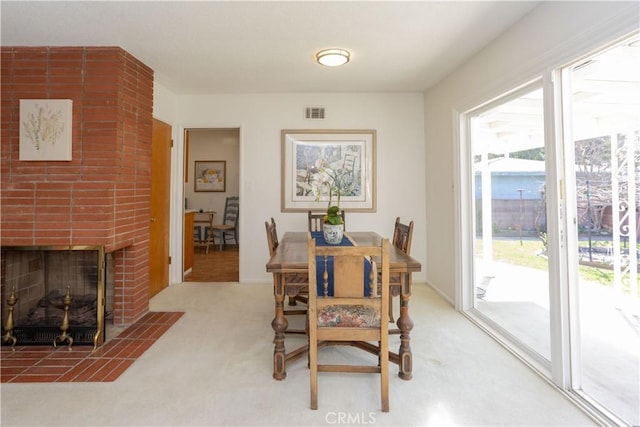 carpeted dining area with a brick fireplace and visible vents