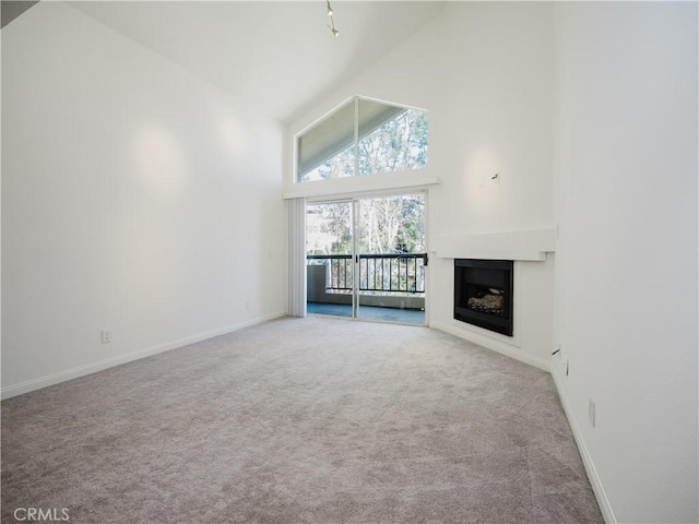 unfurnished living room with high vaulted ceiling, carpet flooring, a fireplace, and baseboards