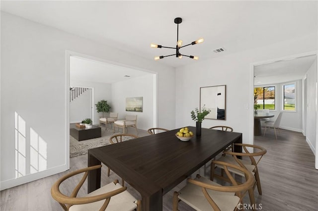 dining area with an inviting chandelier, baseboards, stairway, and wood finished floors