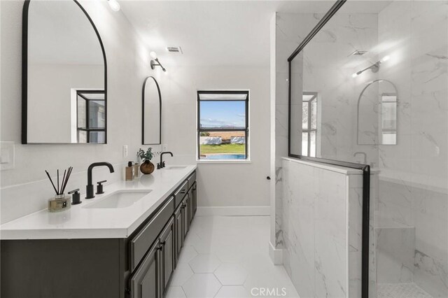 bathroom with baseboards, visible vents, a sink, and a marble finish shower