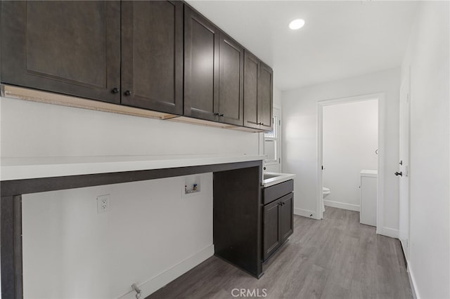 laundry area featuring cabinet space, light wood-style flooring, and baseboards