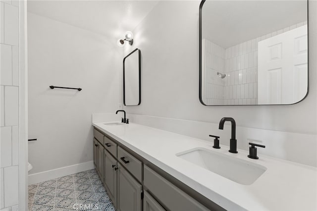 bathroom featuring double vanity, baseboards, a sink, and tile patterned floors