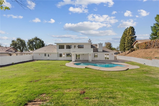 back of property featuring a fenced in pool, a yard, a chimney, a patio, and a fenced backyard