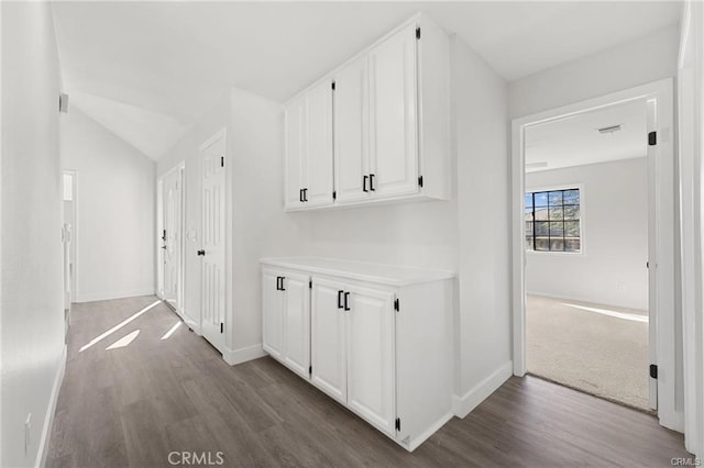 hall with vaulted ceiling, baseboards, and wood finished floors