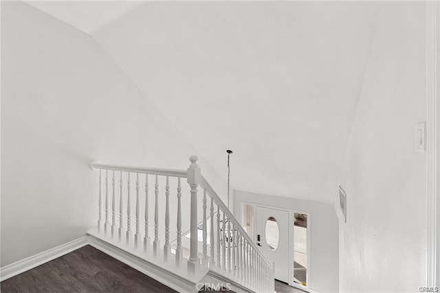 staircase featuring lofted ceiling, baseboards, and wood finished floors