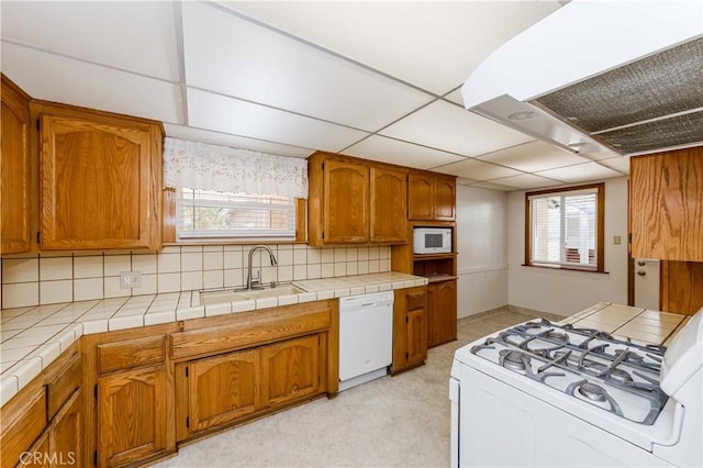 kitchen featuring brown cabinets, white appliances, extractor fan, and a sink