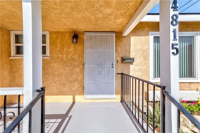 entrance to property with a balcony and stucco siding