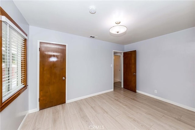 unfurnished room featuring baseboards, visible vents, and light wood-style floors