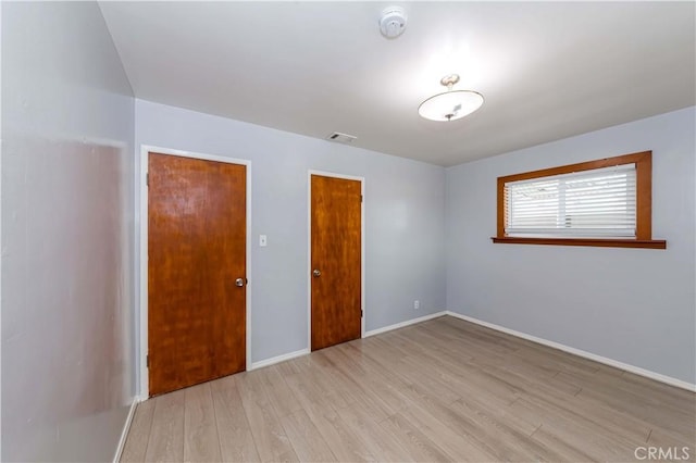 unfurnished bedroom featuring light wood finished floors, visible vents, and baseboards