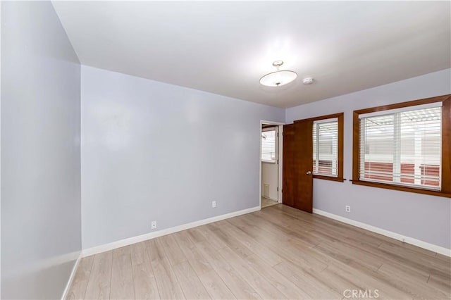 spare room featuring light wood-type flooring, plenty of natural light, and baseboards