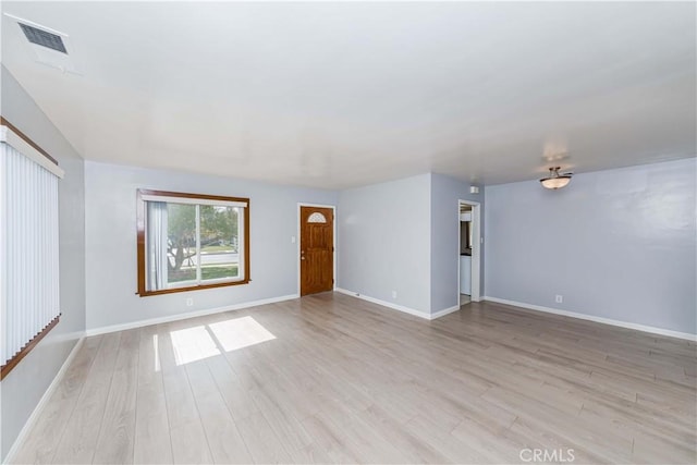 unfurnished room featuring light wood-type flooring, visible vents, and baseboards