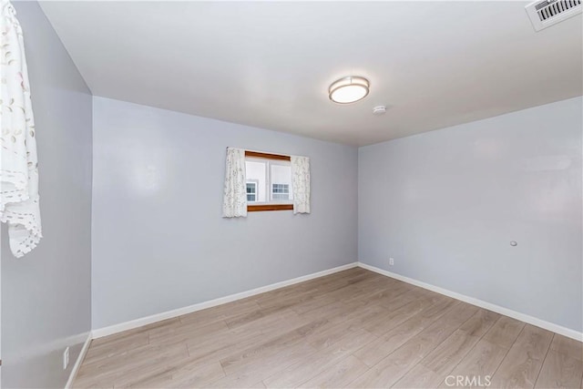 unfurnished room featuring wood finished floors, visible vents, and baseboards