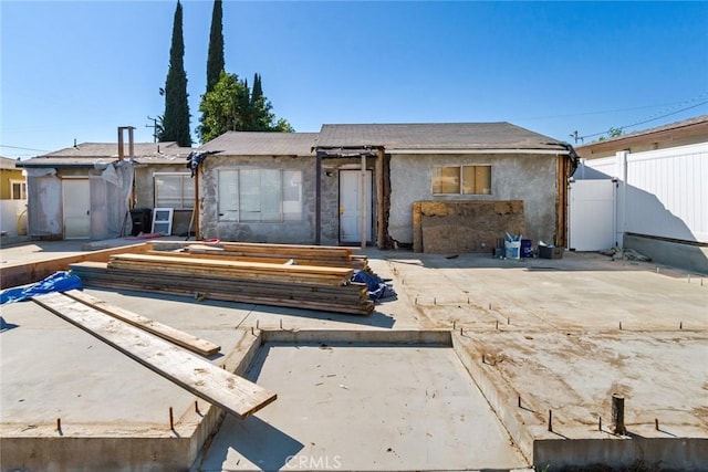 rear view of property with a patio area, fence, a gate, and stucco siding