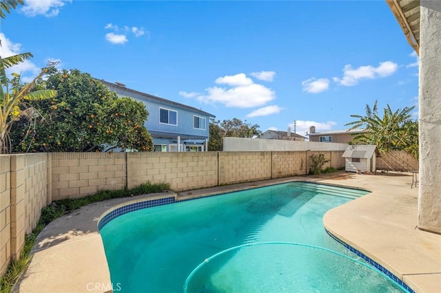 view of pool with an outbuilding, a fenced backyard, a fenced in pool, a storage unit, and a patio area