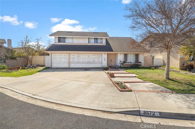 traditional-style house featuring a garage, fence, driveway, stucco siding, and a front lawn