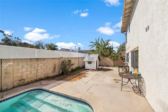 view of pool with an outbuilding, a fenced backyard, a patio, and a shed