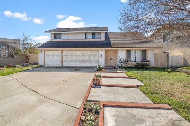 traditional home featuring concrete driveway, stucco siding, an attached garage, fence, and a front yard