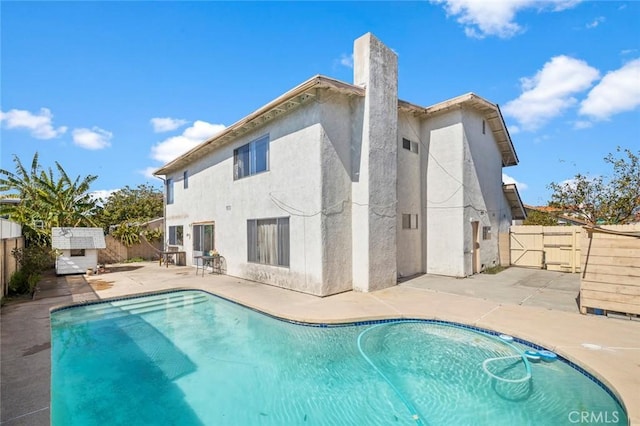 rear view of house with a patio, a fenced backyard, and a fenced in pool