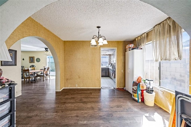 dining space with arched walkways, a textured ceiling, wood finished floors, and baseboards