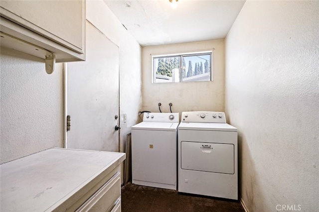 washroom featuring a textured wall, washer and clothes dryer, and cabinet space