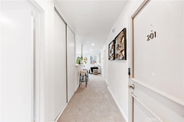 hallway featuring light carpet and baseboards