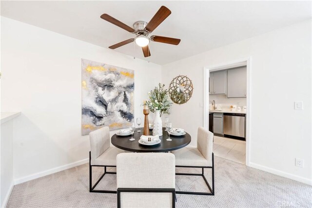 dining room with ceiling fan, light colored carpet, and baseboards