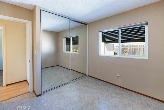 unfurnished bedroom featuring a closet, a textured ceiling, and baseboards