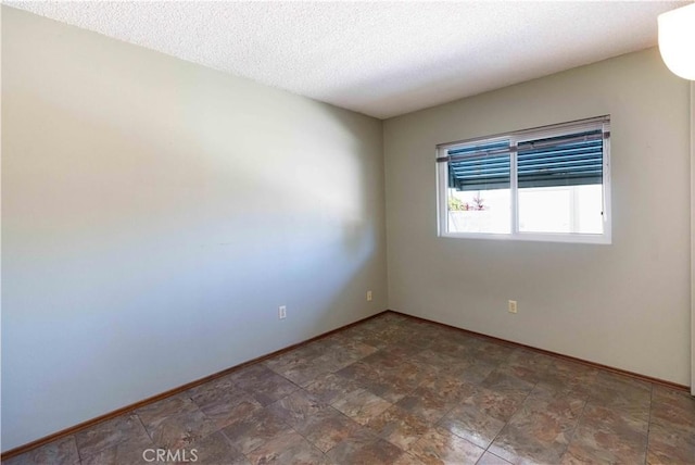 unfurnished room with baseboards and a textured ceiling