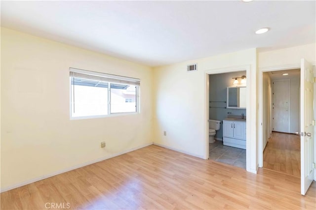 unfurnished bedroom featuring connected bathroom, light wood-style flooring, recessed lighting, visible vents, and baseboards