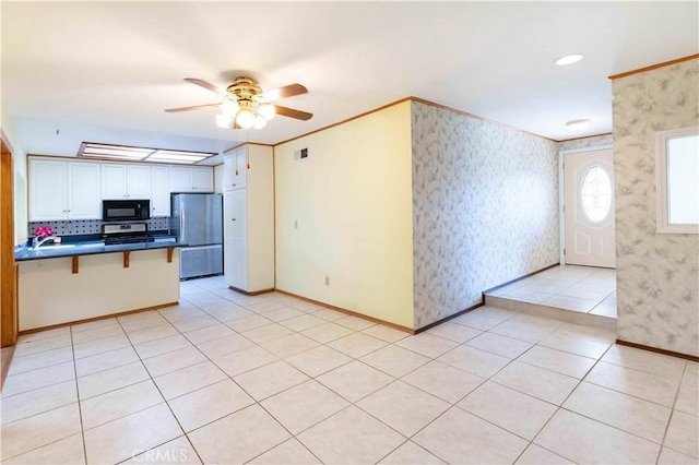 kitchen featuring appliances with stainless steel finishes, dark countertops, visible vents, and wallpapered walls