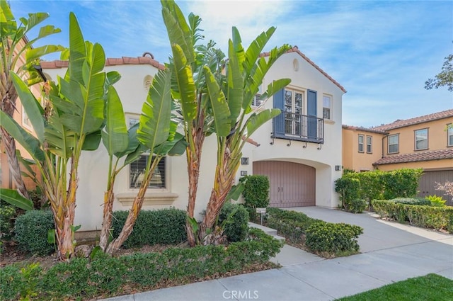 mediterranean / spanish-style home featuring a balcony, a garage, concrete driveway, and stucco siding