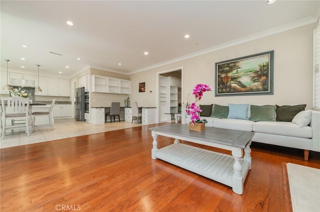 living room with ornamental molding, light wood-style flooring, and recessed lighting