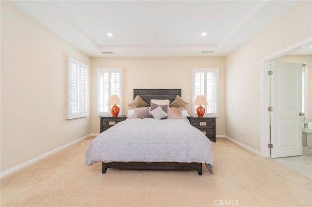 bedroom featuring light carpet, a raised ceiling, visible vents, and baseboards