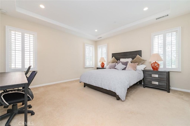 bedroom with multiple windows, a raised ceiling, visible vents, and light colored carpet