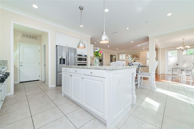 kitchen with light tile patterned flooring, visible vents, ornamental molding, appliances with stainless steel finishes, and a center island