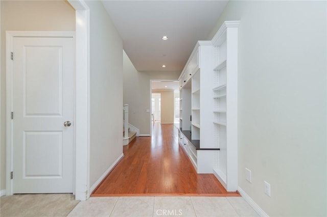 corridor featuring recessed lighting, stairway, baseboards, and light tile patterned floors