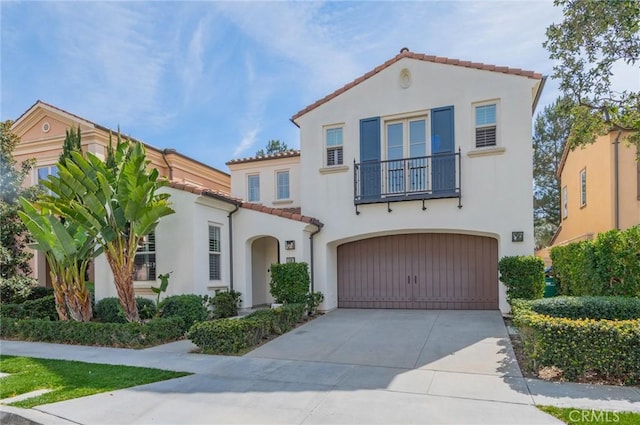 mediterranean / spanish-style house with a balcony, a garage, concrete driveway, a tiled roof, and stucco siding