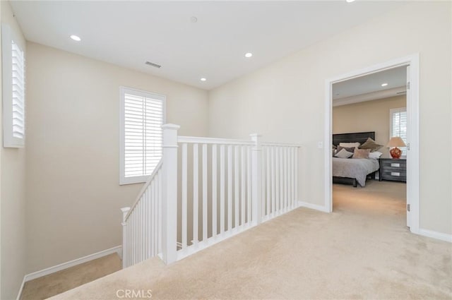 hallway featuring recessed lighting, baseboards, carpet flooring, and an upstairs landing