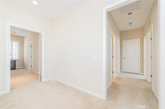 hall featuring light carpet, visible vents, and baseboards