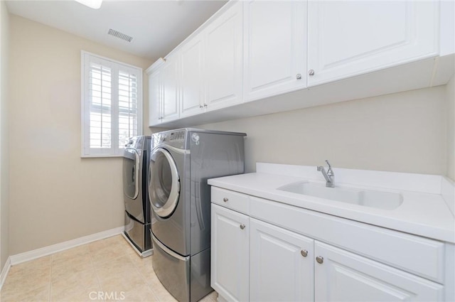 clothes washing area with cabinet space, visible vents, washing machine and dryer, light tile patterned flooring, and a sink